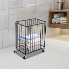 a black metal cage with towels stacked on it in front of a white tiled wall