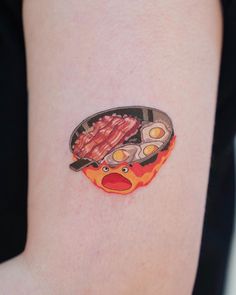 a woman's arm with a plate of bacon and eggs on it