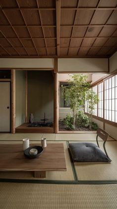 an empty room with wooden flooring and table in front of the window, next to a potted plant