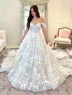 a woman in a white wedding dress standing on a carpeted floor with her hands behind her back