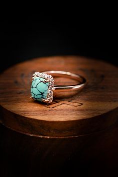 a turquoise stone ring sitting on top of a wooden table