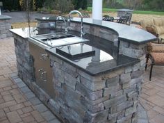 an outdoor kitchen with sink and grill