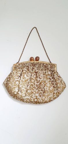 A beautiful gold brocade antique evening bag dating from around 1920. The bag has a brass frame with a simple repeating pattern which fastens with a filigree orb brass kiss clasp. Small brass link chain handle.  Inside the bag has an ivory satin lining with a small side pocket.  The label inside reads 'Made in France'. Condition: This bag is in very good vintage condition. No colour fading, no holes, no external marks. The lining is completely in tact. A few make up marks on the internal pocket and a couple of tiny specks on the lining. See photos. Dimensions:  Frame width: 12.5cm Widest point: 18cm Height: 12cm Chain length: 26cm Shipping note: This item will require a signature upon delivery.  If you have any other questions, please just ask. :-) Elegant Clutch Evening Bag For Vintage Events, Traditional Gold Evening Bag For Formal Events, Traditional Gold Evening Bag For Formal Occasions, Gold Clutch With Gold Embroidery For Formal Occasions, Antique Rectangular Evening Bag For Wedding, Classic Gold Clutch Evening Bag, Vintage Clutch Evening Bag For Events, Antique Style Evening Bag For Weddings, Gold Embroidered Evening Bag For Events