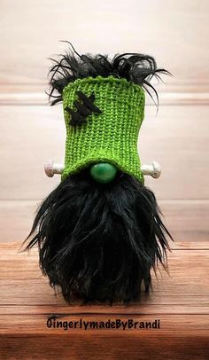 a green knitted hat with black and white hair on top of a wooden table