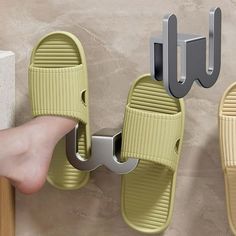 a person's foot is propped up against a wall with two pairs of sandals hanging on it