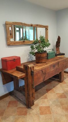 a wooden bench sitting in the middle of a room next to a potted plant