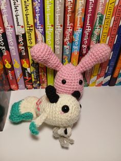 a crocheted stuffed animal sitting in front of a stack of children's books