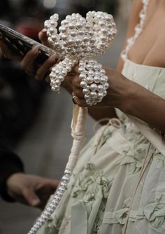 a close up of a person holding a cell phone with pearls on it's arm