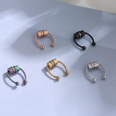 four different types of piercings on a table with one being gold, the other is silver