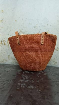 "Unique and stylish burned orange sisal kiondo bag with stitched leather straps. Ideal as a beach bag, shopping basket, market basket or storage basket. This unique tote bag is handmade by a group of ladies in a remote rural village in Machakos, Kenya. Do not clean with water. If the bag gets wet, please dry to avoid dampness.  Leather type used is bovine, from cattle. It's natural and in it's purest form. DIMENSIONS Bottom width: 10\"/25.5cm Top width: 14\"/35.56cm Depth: 10\"/25.5cm Straps: 15\"/38cm SHIPPING All orders ship via DHL Express (3-5) days delivery time." Woven Leather Bucket Shoulder Bag, Brown Straw Bucket Bag For Everyday Use, Casual Brown Woven Bucket Bag, Eco-friendly Woven Leather Crochet Bucket Bag, Brown Woven Leather Basket Bag, Brown Straw Bucket Shoulder Bag, Woven Leather Basket Bag For Shopping, Brown Woven Straw Shoulder Bag, Bohemian Brown Bucket Bag With Double Handle