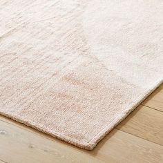 a white rug on top of a wooden floor next to a wood floor with a light colored area rug