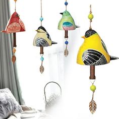 three colorful birds hanging from the ceiling next to a bed with pillows and blankets on it