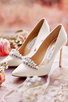 the brides wedding shoes are adorned with swarozak crystals and pearls, along with pink roses