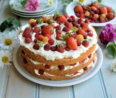 a cake with strawberries on top is sitting on a pink plate next to yellow flowers