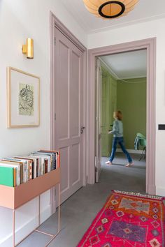 a woman walking through a hallway next to a pink rug