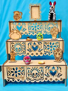 three tiered display case with wooden cutouts and decorative items on top, against a blue background