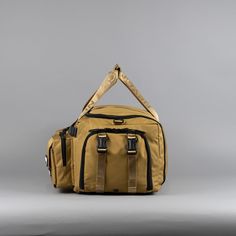 a tan duffel bag sitting on top of a gray floor next to a wall