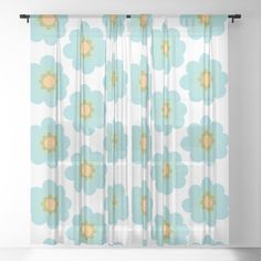 a curtain with blue and yellow flowers on the outside, in front of a white wall