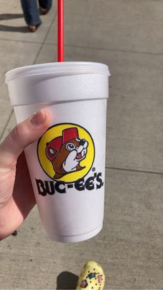 a person holding up a cup with a straw in it's hand and a sticker on the side