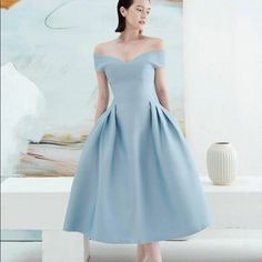 a woman standing in front of a painting wearing a blue dress