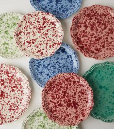 six plates with speckles on them sitting next to each other in different colors