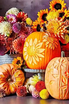 an arrangement of pumpkins and flowers on a table