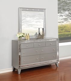 a silver dresser with two vases and a mirror