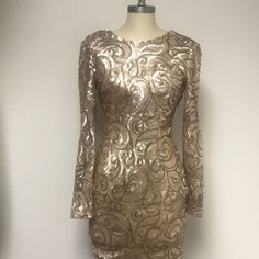 a gold dress on a mannequin stand in front of a white wall and floor