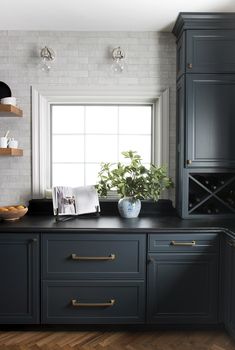 a kitchen with black cabinets and white brick walls, wood flooring and open shelves