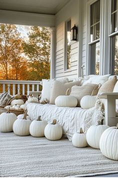 a porch with pumpkins and pillows on it