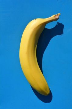 a yellow banana sitting on top of a blue surface