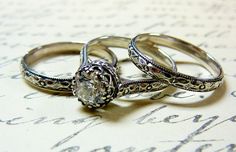 two wedding rings sitting on top of an old book with writing in the back ground