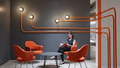 a woman sitting in an orange chair next to a table with two chairs on it