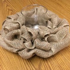 a glass sitting on top of a wooden table next to a burlocked cloth