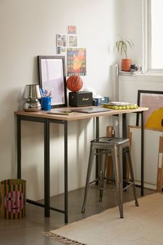 a desk with various items on it in a room next to a chair and table