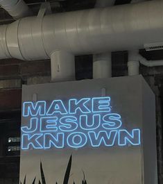 a sign that says make jesus known in blue lights on the side of a building