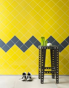 a pair of shoes sitting on top of a stool in front of a yellow wall