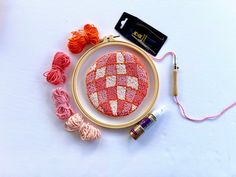 a red and white ball of yarn sitting on top of a table next to some thread