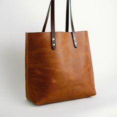 Meet your new everyday bag. Simple construction and soft lines make for a bag that'll never go out of style and will only get better with age. Premium Full-grain leather, robust stitching and solid brass hardware for a lifetime of service, guaranteed. -11" Shoulder Drop -Interior Accessory Pocket Dimensions: 14" x 13.5" x 6" Enjoy a complimentary, monogrammed Bag Tag. Simply place your monogram in the monogram box below. Everyday Bags With Leather Handles And Vegetable Tanned Leather, Modern Satchel With Brass Hardware, Modern Everyday Satchel With Brass Hardware, Classic Everyday Bag In Vegetable Tanned Leather, Vegetable Tanned Leather Satchel With Double Handle, Classic Vegetable Tanned Leather Bags For Everyday, Modern Leather Satchel With Brass Hardware, Classic Everyday Shoulder Bag In Vegetable Tanned Leather, Classic Vegetable Tanned Leather Shoulder Bag For Everyday