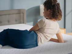 a woman laying on top of a white bed