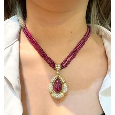 This is part of Chairish’s Fine Jewelry assortment.  This captivating pendant necklace, showcases a mesmerizing 22.41 carat, deep pink ruby cabochon cut, securely set in a classic bezel mounting crafted from 18k yellow gold. The weight of the piece is 27.57 grams. GRS certified, the ruby is surrounded by 144 sparkling diamonds and further complemented by 7 elegant emerald cut diamonds, totalling approximately 13-15 carats. A beaded ruby chain completes this luxurious and unique statement piece. Diamond Cabochon Pendant Necklace, Luxury Pear-shaped Ruby Jewelry, Luxury Red Cabochon Necklaces, Luxury Red Cabochon Necklace, Elegant Cabochon Teardrop Pendant Necklace, Elegant Teardrop Pendant Cabochon Necklace, Luxury Yellow Gold Ruby Necklace, Luxury Ruby Necklace In Yellow Gold, Elegant Ruby Oval Pendant Necklace