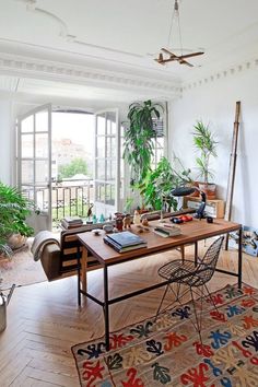 an image of a living room setting with plants on the table and books on the floor