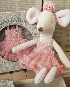 a stuffed mouse in a pink dress sitting on top of a box