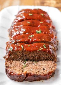 sliced meatloaf on a white plate with sauce and parsley sprinkled on top