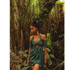 a woman in a green dress walking through the jungle