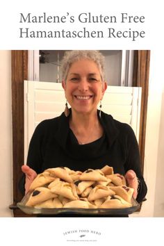 a woman holding a tray full of food in front of her face and the words marnie's gluten free hamantaschen recipe