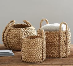 three woven baskets sitting on top of a wooden table next to a stack of books