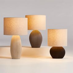 three lamps with different shapes and sizes on them, one is white and the other is brown