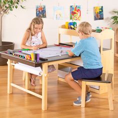 two children sitting at a table playing with toys