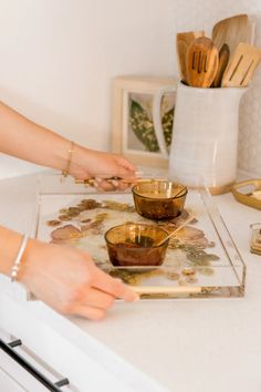 a woman is mixing some food in a bowl on the kitchen counter with wooden utensils